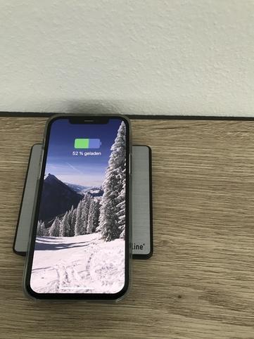 Geschlossene Steckdose mit iQ-Ladefunktion mit Smartphone das gerade geladen wird