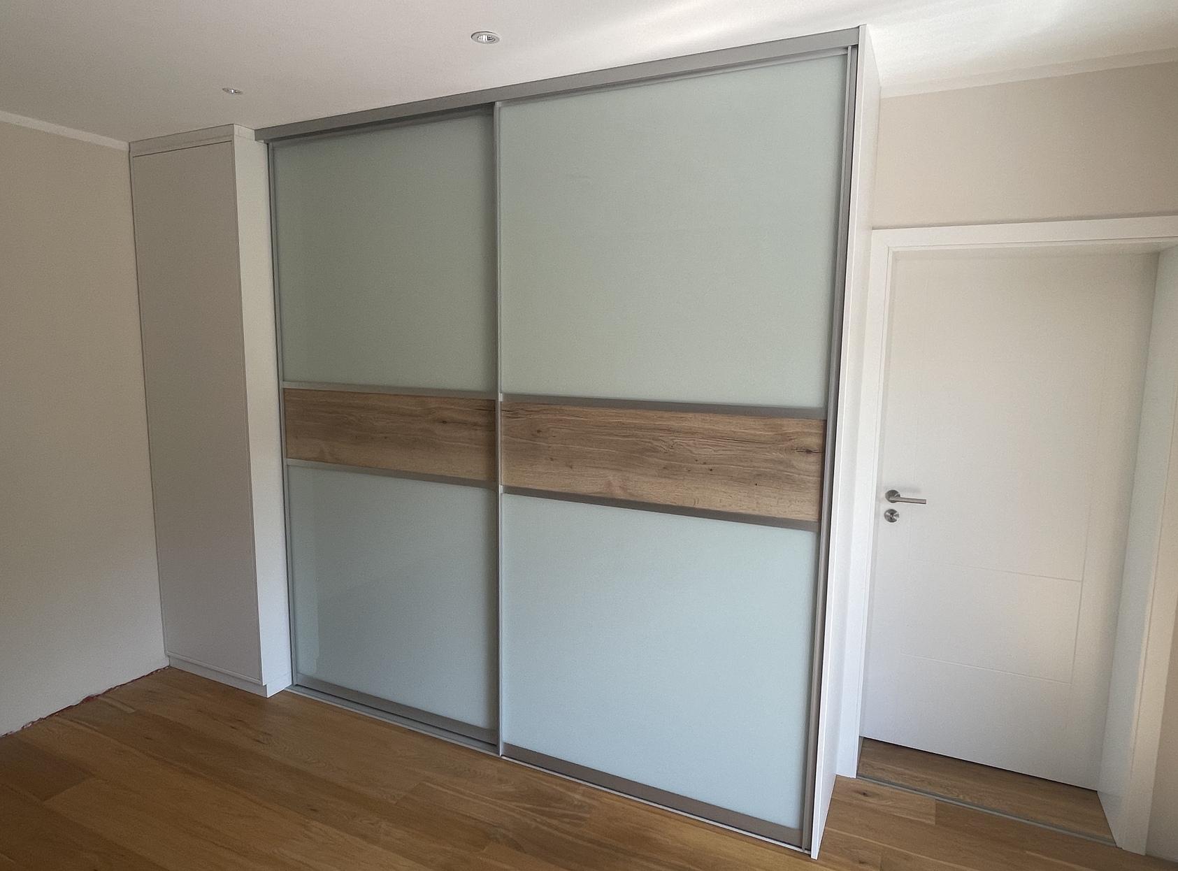 Kleiderschrank mit Schiebetürenfüllung aus Lackglas und Holz