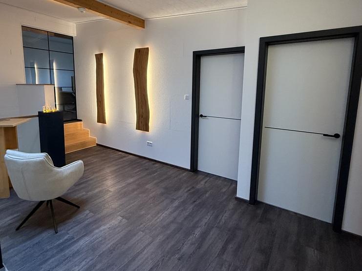 Flur und Treppenhausgalerie mit Möbelfeuersäule, handgeferigte Olivenholz-Wandleuchten, weisse Innentüren mit schwarzer Lisene