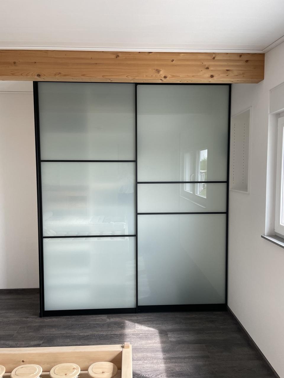 Raumhoher Kleiderschrank mit Alurahmen-Gleitschiebetüren in schwarz mit satinierten Glaseinsätzen Kleiderschrank mit Gleitschiebetüren aus schwarzen Alurahmen und satinierten Glaseinsätzen