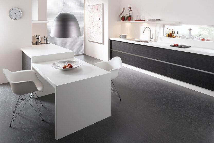 Impression einer einzeiligen Küchengestaltung in schwarz-weiß mit Esstisch für Zwei