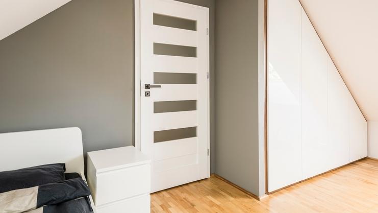 Weißer Einbauschrank an Dachschräge Weißer Einbauschrank an Dachschräge, dreieckig mit Trennwand zur Zimmertür an hellem Parkett.