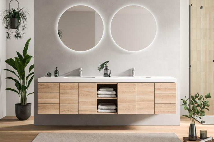 Stilvolles Bad nach Maß mit einem Doppelwaschtisch, Holzschubladen und runden, beleuchteten Spiegeln, umrahmt von Pflanzendekor.